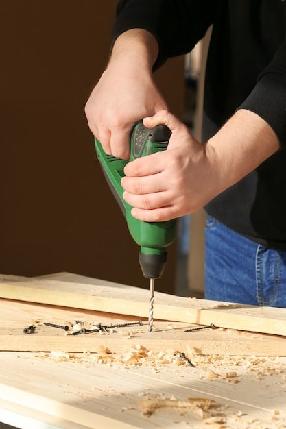 Close-up of a person attaching a plywood sheet to the wooden frame of a workbench, using a power drill.