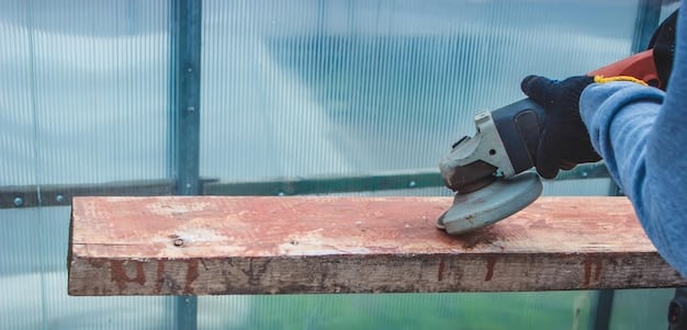A worker using a circular saw to cut a deck board. They are wearing safety glasses and gloves. The sawn deck board is laid on top of existing deck joists supported on concrete piers.