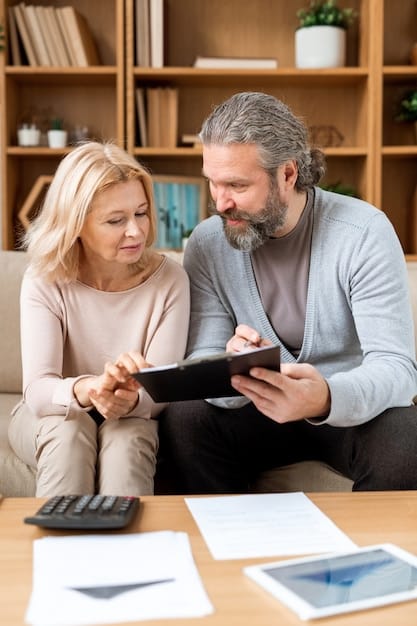 A parent studying documents with a calculator and financial reports on the table, showcasing financial planning and strategy.