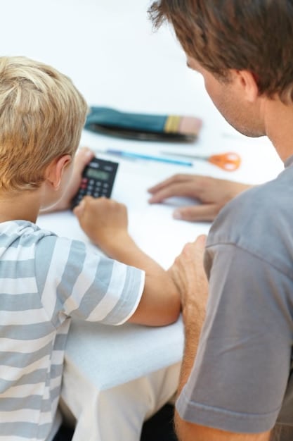 A close-up shot of a father's hands reviewing financial documents and using a calculator at his desk, with a photo of his child visible in the background. Stress is visible.